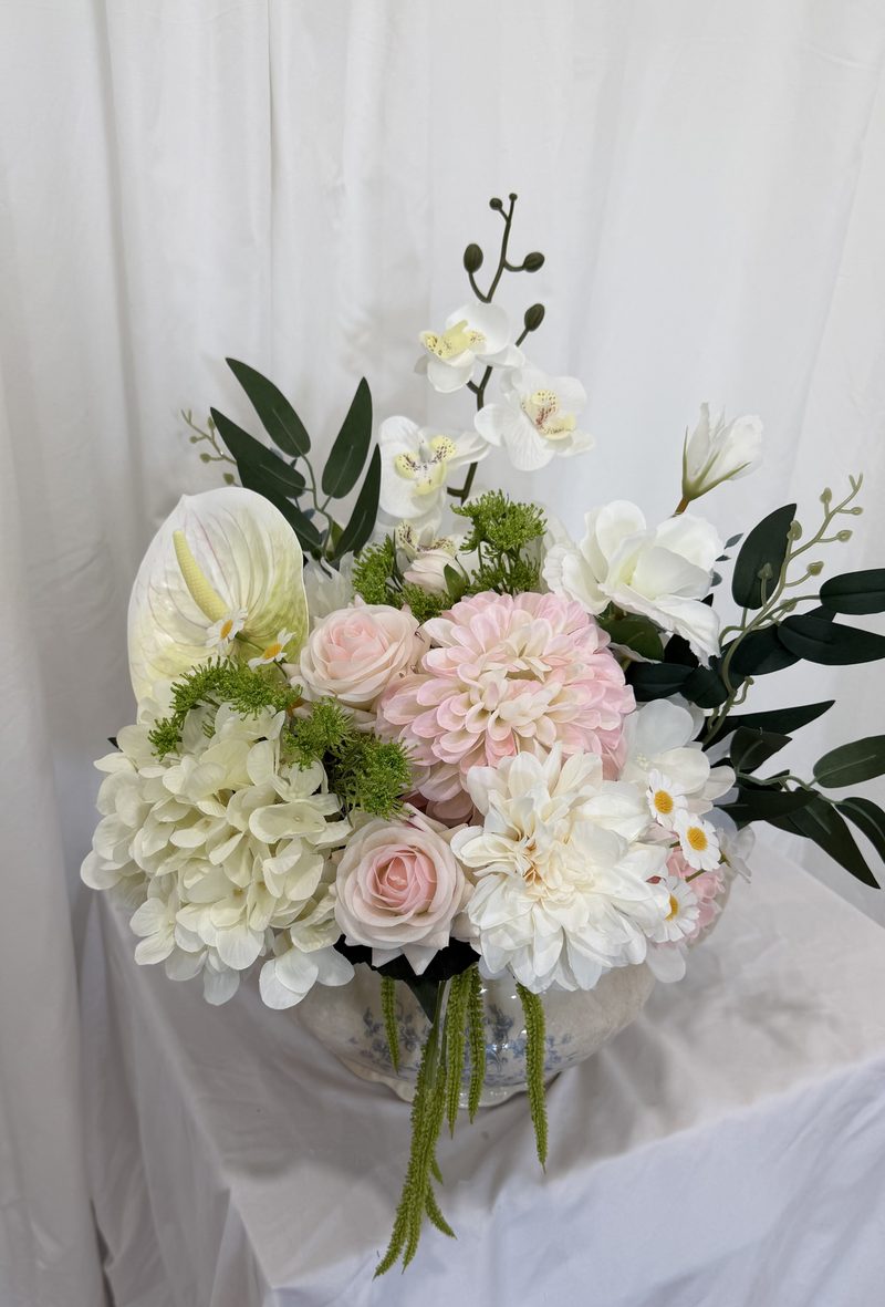 Low, wide bar arrangement of ivory and blush florals with trailing greenery