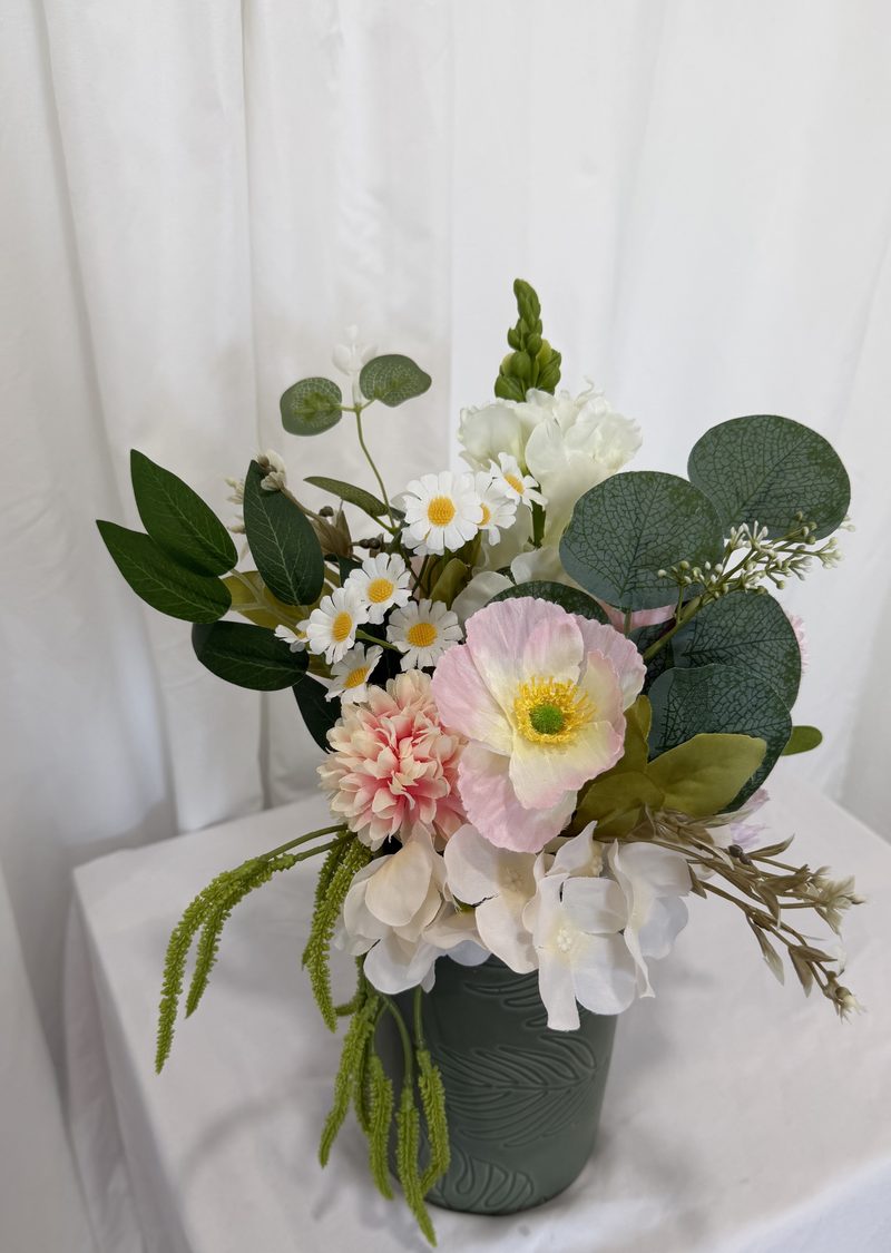 Rounded arrangement with eucalyptus and blush blooms in a matte green vessel