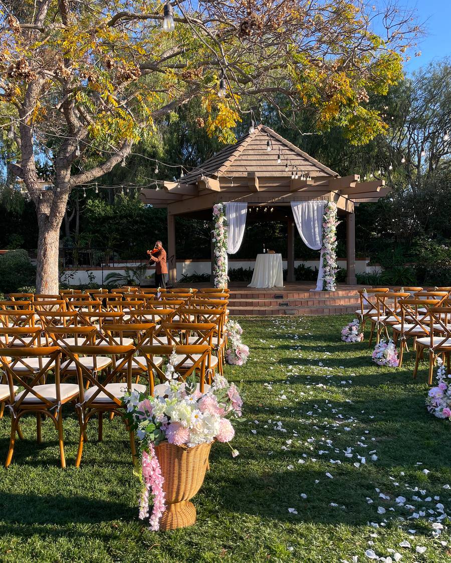 Ceremony set with two large floral installations on the pergola, meadow arrangements along the aisle and a pedestal arrangement in the foreground